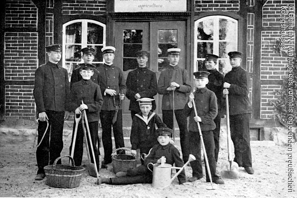 Die Prinzen August Wilhelm, Oskar und Joachim von Preußen mit ihren Mitschülern bei der Gartenarbeit vor dem Bauernhaus, Prinzeninsel Plön